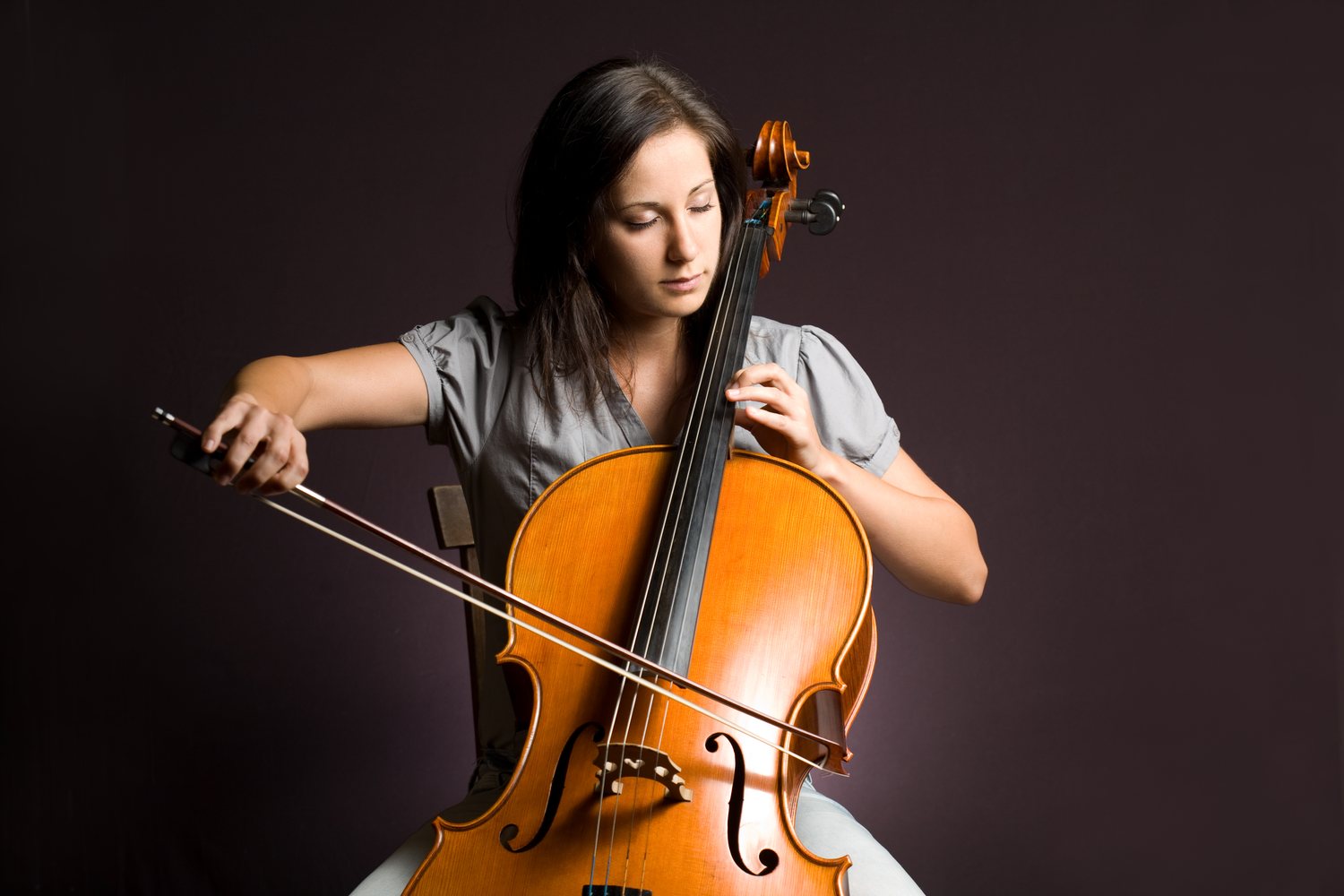 Cellistin spielt Cello auf einem passenden Stuhl